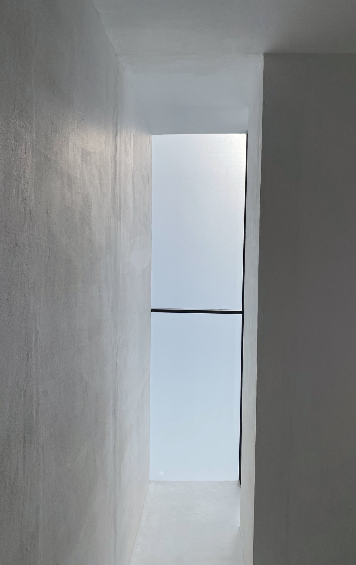 Pasillo estrecho que termina en un vano de luz. Casa RC.
